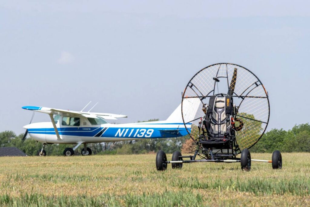 Paramotor mounted on a Basik trike with a small plane in the background, showcasing aviation synergy.